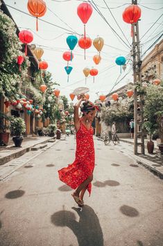 a woman in a red dress is walking down the street