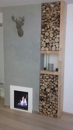 a living room with a fire place and wood stacked on top of each other in front of a wall mounted deer head