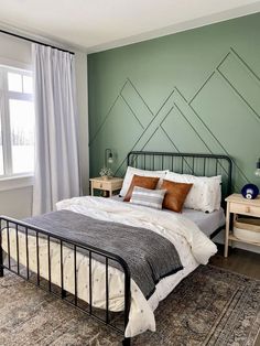 a bedroom with green walls and a metal bed frame in the middle, along with a rug on the floor