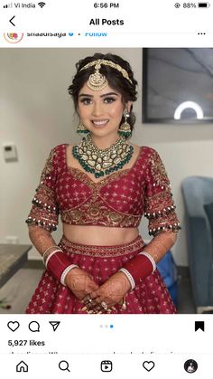 a woman in a red and gold bridal outfit with jewelry on her head, smiling at the camera