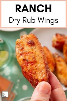 a hand holding up a piece of chicken wings with the words ranch dry rub wings above it