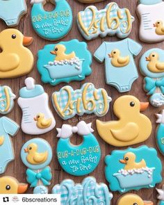 baby shower cookies decorated with blue and yellow icing on a wooden table in the shape of ducks