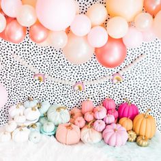 there are many balloons and pumpkins on the floor next to each other in front of a wall