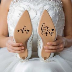 the bride is holding her wedding shoes with their names on them and they are both wearing heels