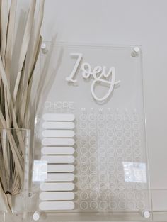 a clear acrylic sign with white lettering on it and some straws in front of it