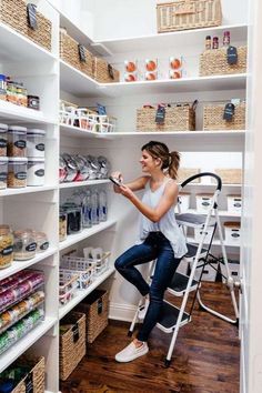 a woman standing on a ladder in a pantry with shelves full of food and supplies