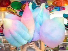 a woman holding two large cotton candy lollipops in front of her face