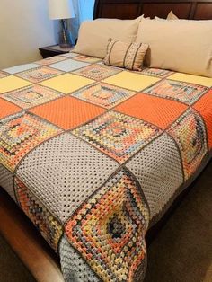 a bed with an orange and gray quilt on it