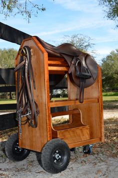 a wooden horse trailer with a saddle on it's back and two black wheels