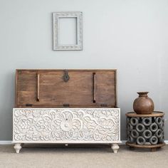 a white chest sitting on top of a carpeted floor next to a brown vase