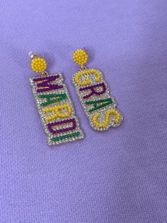 Get ready to dazzle at your next Mardi Gras parade with these purple, green, and gold rhinestone earrings! Add a touch of sparkle to your outfit and let the good times roll with these festive earrings. Perfect for celebrating in style! Purple Party Earrings With Sparkling Stones, Purple Sparkling Stones Earrings For Party, Party Purple Crystal Rhinestone Earrings, Purple Rhinestone Crystal Earrings For Party, Purple Rhinestone Drop Earrings, Purple Jewelry For Mardi Gras, Purple Rhinestone Party Earrings, Purple Rhinestone Earrings For Party, Purple Beaded Earrings For Party