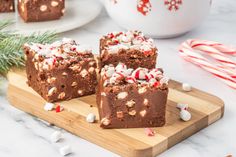 three brownies with candy canes and marshmallows on a cutting board