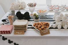 a table topped with lots of food next to a bowl of fruit and cupcakes