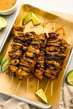 grilled chicken skewers with cilantro and limes on a tray