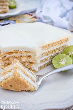 a piece of cake on a white plate with a fork and lime slice next to it