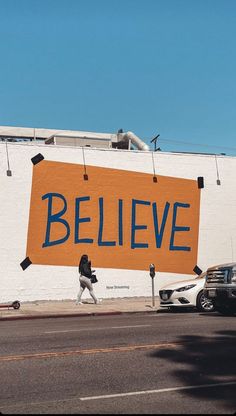 a large sign that says believe on the side of a building next to a street