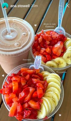 two plastic cups filled with fruit and strawberries on top of a wooden table next to each other