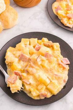 an omelet with ham and cheese is on a black plate next to bread