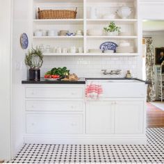 a kitchen with white cabinets and black counter tops is pictured in this image, there are dishes on the shelves