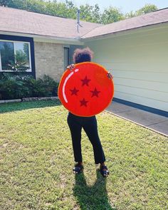 a woman is standing in the grass holding up a red sign with stars on it