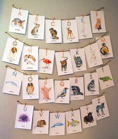 several cards are hanging on a clothes line with animals and letters attached to them that spell out the letter s