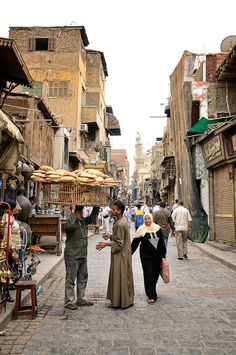 several people are walking down an alleyway in the old part of town, one is talking to another person