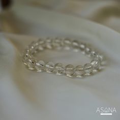 Introducing Asana Crystals' Clear Quartz Bracelet—a timeless and versatile accessory that embodies clarity, purity, and positive energy. Handcrafted from natural Clear Quartz, each bead in this bracelet exudes a pristine transparency symbolizing clarity of mind and spirit. Known as the "master healer," Clear Quartz amplifies energy, enhances intuition, and promotes overall well-being. Featuring smooth, round beads measuring 8mm, this bracelet offers a classic elegance suitable for any style or occasion. With no closure, the beaded stretch design ensures effortless wearability and comfort, allowing you to carry the uplifting energy of Clear Quartz throughout your day. Embrace the pure and transformative energy of Clear Quartz and elevate your look with Asana Crystals' Clear Quartz Bracelet— Adjustable Clear Crystal Bracelet With Round Beads, White Adjustable Crystal Bracelet, Adjustable Clear Round Bead Crystals, Spiritual Clear Round Beaded Bracelets, Clear Spiritual Beaded Bracelets, Elegant Crystal Bracelet With Clear Round Beads, Elegant 8mm Beads Crystal Bracelet For Meditation, Minimalist Round Crystal Bracelet With Gemstone Beads, Elegant Crystal Bracelet With 8mm Beads For Meditation