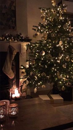 a lit christmas tree in front of a fireplace