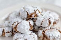 a pile of powdered sugar covered cookies on a white plate