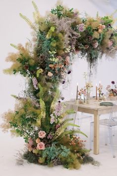 a table topped with lots of flowers and greenery next to a tall arch made out of plants