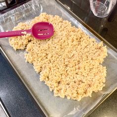 a baking pan with oatmeal in it and a pink spoon on top