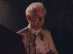 an older man with white hair wearing a brown jacket and tie in a dark room