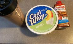 an ice cream container next to a blender and coffee cup on a counter top