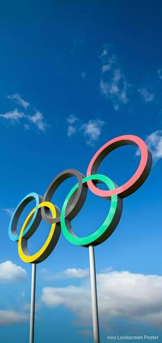 the olympic rings are on poles in front of a blue sky