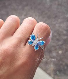 Blue Topaz CZ butterfly silver ring, clear - butterfly ring, silver ring, promise ring - 925 sterling silver  Height: 16.0mm Width: 17.0mm Shank Width: 1.7mm Stone Material: Blue Topaz CZ and White Cubic Zirconia Center Stone Size: 7.0mm x 5.0mm & 6.0mm x 4.0mm Stone Shape: Pear and Round Center Stone Carat Weight: 0.71 ct. & 0.39 ct. Number of CZ Stones: 8 Stone Setting: Prong Metal: 925 Sterling Silver Plating: Rhodium Finish: High Polish simply stunning. High Polished, solid 925 sterling silver. Rhodium plated to prevent tarnishing. TARNISH FREE Rhodium plated to avoid tarnishing Nothing but the best from my custom jewelry store. Email me if you have any questions. Adjustable Cubic Zirconia Butterfly Open Ring, Elegant Blue Sterling Silver Butterfly Ring, Silver Butterfly Fine Jewelry, Adjustable Cubic Zirconia Butterfly Promise Ring, Adjustable Butterfly Ring With Cubic Zirconia, Butterfly Shaped Cubic Zirconia Fine Jewelry Rings, Butterfly-shaped Cubic Zirconia Fine Jewelry Rings, Butterfly Ring With Cubic Zirconia As A Gift, Butterfly-shaped Cubic Zirconia Rings As Gifts