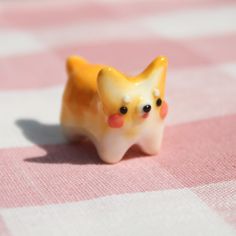 a small yellow dog figurine sitting on top of a pink and white checkered table cloth