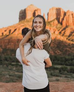 a man carrying a woman on his back in front of a mountain range at sunset