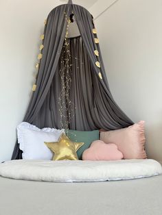 a bed that has some pillows on top of it and gold stars hanging from the ceiling