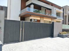 a large house with a fence and some plants in front of the gated entrance