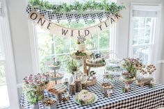 a table topped with lots of food and desserts next to a window covered in greenery