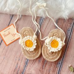 a pair of crocheted sandals with an orange and white flower on the front