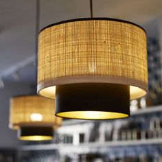 three lamps hanging from the ceiling in a restaurant or bar with bamboo shades on them