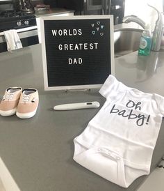 a sign that says world's greatest dad next to some baby clothes and shoes