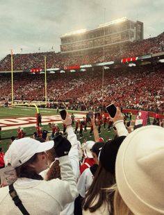 people taking pictures at a football game with their cell phones