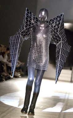 a woman walking down a runway with an umbrella on her head and body covered in mesh