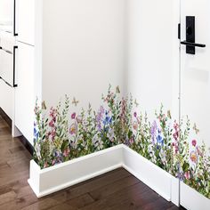 a kitchen wall with flowers painted on it and a white refrigerator in the back ground