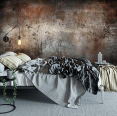 a bed sitting in front of a wall with a lamp on it's side