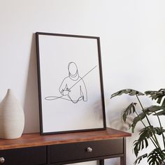 a black and white drawing sitting on top of a wooden table next to a potted plant