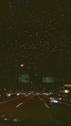 the night sky is filled with stars and street signs, as well as cars driving down it