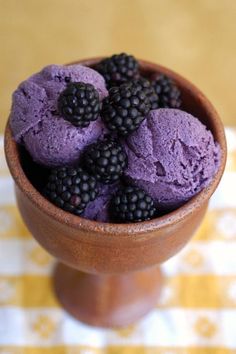 a bowl filled with purple and blackberries on top of a table